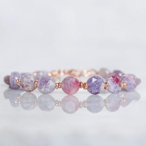 Könnte beinhalten: Ein Armband aus violetten und rosafarbenen Edelsteinperlen mit roségoldenen Akzenten.