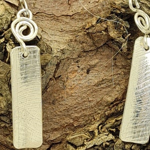 May include: A pair of silver earrings with a textured rectangular pendant and a twisted wire detail.