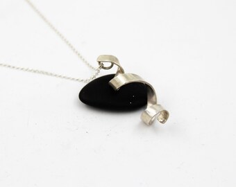Può includere: Una collana d'argento con un ciondolo di pietra nera e un design a spirale argentato.