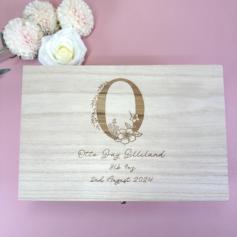 May include: A light wood keepsake box with an engraved floral design and the letter "O". The box also has the text "Otto Gray Gilliland 8lb 1oz 2nd August 2024" engraved on it.