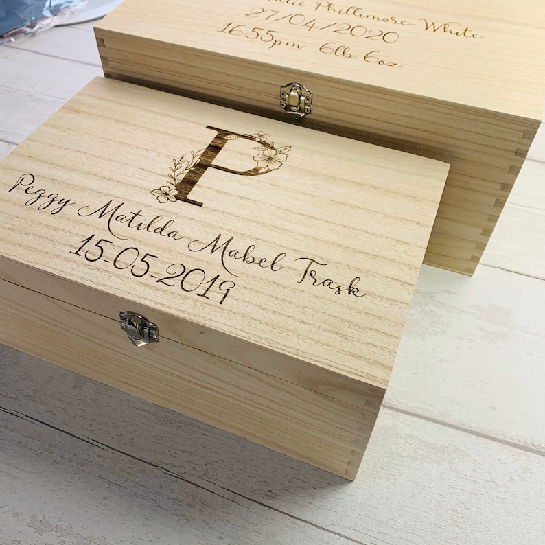 May include: A wooden keepsake box with a floral design and the letter "P" engraved on the lid. The box is personalized with the name "Peggy Matilda Mabel Trask" and the date "15-05-2019".