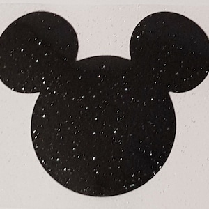 May include: Black glitter Mickey Mouse silhouette on a white background.