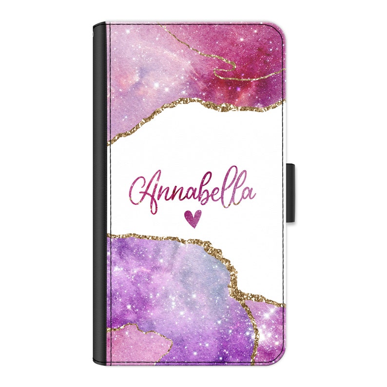 May include: A pink and purple galaxy-inspired phone case with gold glitter accents. The case has a white background with the name "Annabella" written in pink script and a small pink heart.