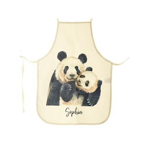Peut inclure: Un tablier de cuisine beige avec une illustration aquarelle de deux pandas qui se font un câlin. Le tablier porte le nom "Sophia" imprimé en bas.