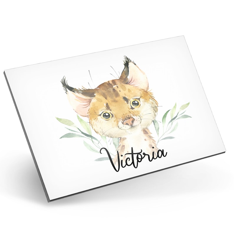 Puede incluir: Una ilustraci&oacute;n de acuarela de un lindo lince con hojas verdes detr&aacute;s. El nombre "Victoria" est&aacute; escrito en cursiva debajo del lince.