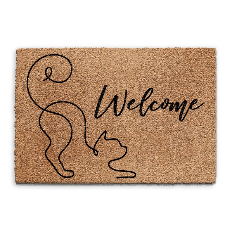 May include: A brown coir doormat with the word "Welcome" in black cursive lettering. A black line drawing of a cat with its tail curled around its body is on the left side of the mat.