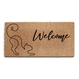 May include: A brown coir doormat with the word "Welcome" in black cursive lettering. A black line drawing of a cat is on the left side of the mat.