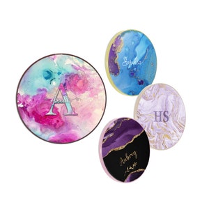 May include: Four round coasters with abstract watercolor designs and gold accents. Each coaster features a different name: Amelia, Sophia, Aubrey, and HS.