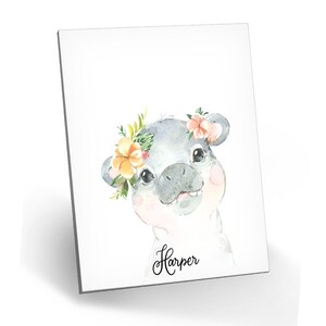 Puede incluir: Una ilustraci&oacute;n de acuarela de un lech&oacute;n gris con una corona de flores con flores naranjas y rosas. El lech&oacute;n est&aacute; mirando al espectador y tiene la nariz rosa. El texto "Harper" est&aacute; escrito debajo del lech&oacute;n.