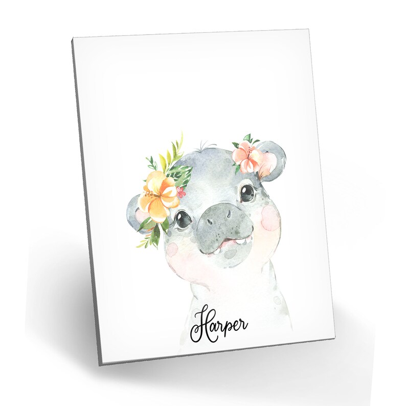 Puede incluir: Una ilustraci&oacute;n de acuarela de un lech&oacute;n gris con una corona de flores con flores naranjas y rosas. El lech&oacute;n est&aacute; mirando al espectador y tiene la nariz rosa. El texto "Harper" est&aacute; escrito debajo del lech&oacute;n.
