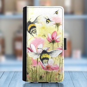 May include: A white phone case with a floral design and bees. The flowers are pink and yellow and the bees are black and yellow.