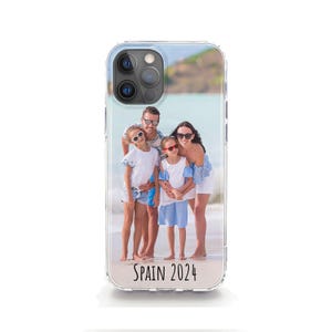 May include: A clear phone case with a photo of a family of four on a beach. The photo shows a man, a woman, and two children. The text "SPAIN 2024" is printed on the case.