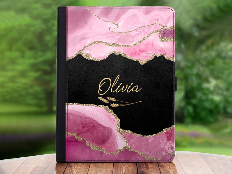 Peut inclure: Une coque de tablette rose et noire avec un motif de paillettes dor&eacute;es et le nom "Olivia" &eacute;crit en lettres dor&eacute;es.