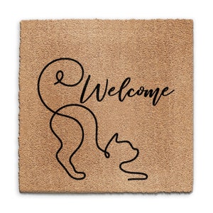 May include: A brown coir doormat with the word "Welcome" written in black cursive script. A stylized black line drawing of a cat is to the left of the word "Welcome".