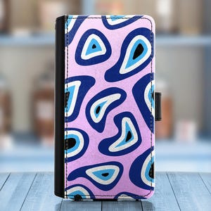 May include: A pink phone case with a blue and white abstract pattern. The pattern resembles a series of stylized eyes.