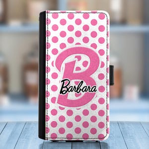 May include: A pink and white polka dot phone case with a large pink letter "B" and the name "Barbara" in black text.