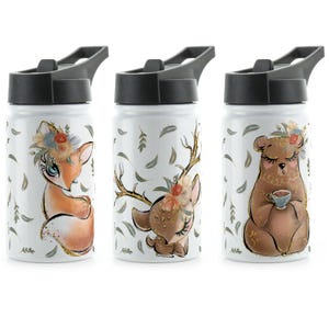 May include: Three white stainless steel water bottles with black lids and different animal designs. The first bottle features a fox with a floral crown, the second bottle features a deer with antlers and a floral crown, and the third bottle features a bear holding a cup of tea.