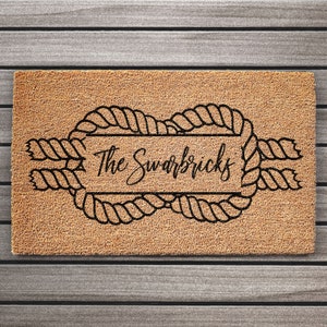 May include: A brown coir doormat with a black rope design and the text "The Swarbricks" in a cursive font.