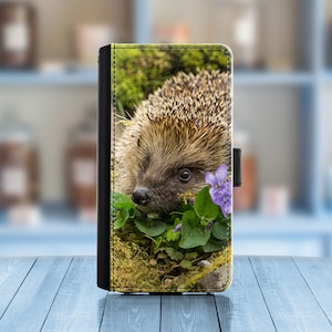 May include: A close-up of a hedgehog with brown and white spines, looking to the left. The hedgehog is surrounded by green leaves and purple flowers.