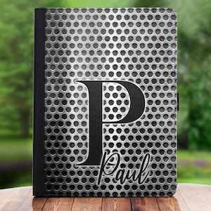 May include: A black and silver personalised iPad case with a metal grid pattern and the letter "P" and the name "Paul" in black.