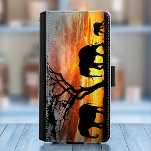 May include: A black phone case with a sunset scene and silhouettes of elephants walking in a line. The background is a vibrant orange and yellow sunset with a dark tree in the foreground.