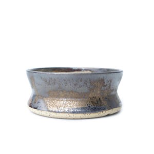 May include: A handcrafted ceramic bowl with a unique shape and metallic glaze. The bowl features a dark gray exterior with gold accents and a light beige base. This decorative bowl is suitable for serving or display.
