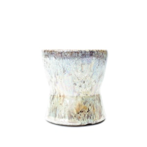 May include: A ceramic cup featuring a flared rim and a tapered base. The exterior surface displays a reactive glaze with a blend of iridescent light blue, cream, and earthy brown tones, creating a mottled, crystalline texture across the entire body.