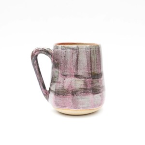 May include: A ceramic mug with a pink and gray plaid pattern. The mug has a rounded body and a handle.