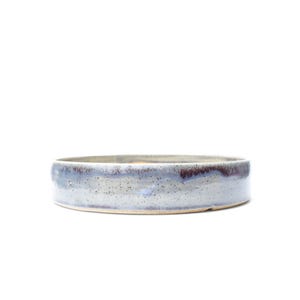 May include: A shallow, circular ceramic bowl with a speckled light gray and blue glaze. The exterior features a smooth, cylindrical wall with a distinct horizontal band of darker, mottled blue and brown tones near the upper rim edge.