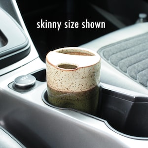 Puede incluir: Una taza de cer&aacute;mica con un esmalte marr&oacute;n y blanco moteado y un esmalte verde en la parte inferior. La taza est&aacute; sentada en un portavasos de coche. "Skinny size shown" est&aacute; escrito en texto blanco sobre un fondo negro encima de la taza.
