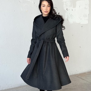 Long hooded coat with a princess-inspired design in warm, heavy wool with soft viscose lining, perfect for winter. Features side pockets and a long belt at the waist for a flattering fit.
