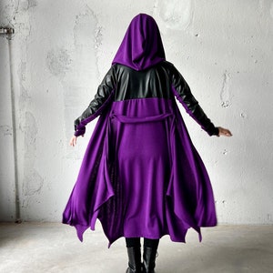 May include: A purple hooded cloak with black leather accents. The cloak has a long, flowing design and is cinched at the waist with a belt.