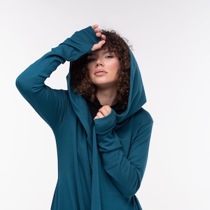 Puede incluir: Una chaqueta de punto azul turquesa con capucha, mangas largas y un dobladillo fluido.