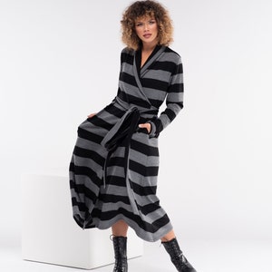 May include: A long, striped robe in black and grey, featuring a wrap-around design and a matching belt. The robe has long sleeves and pockets. The person is wearing black lace-up boots.