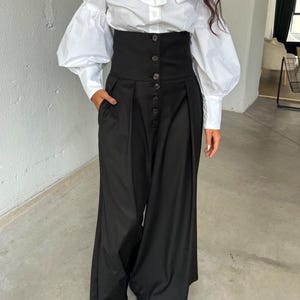 High waisted pants with wide leg design, side pockets, and front buttons.
