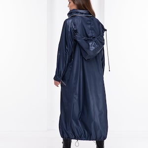 May include: A long, navy blue raincoat with a drawstring hood. The raincoat has a zipper closure and a cinched waist.