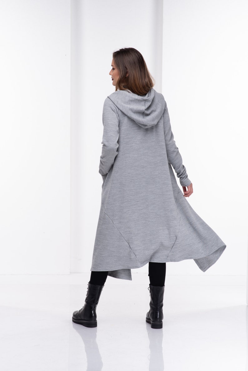 Pu&ograve; includere: Un lungo cardigan con cappuccio grigio con un orlo asimmetrico e fluido. Il cardigan &egrave; realizzato in un tessuto morbido e confortevole e ha una vestibilit&agrave; rilassata.