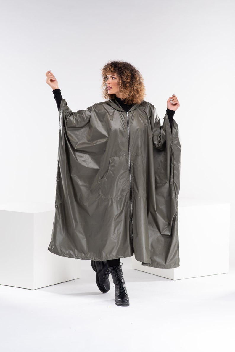 May include: A hooded, long, olive green raincoat with a zipper closure and pockets. The raincoat is made of a shiny, water-resistant material.