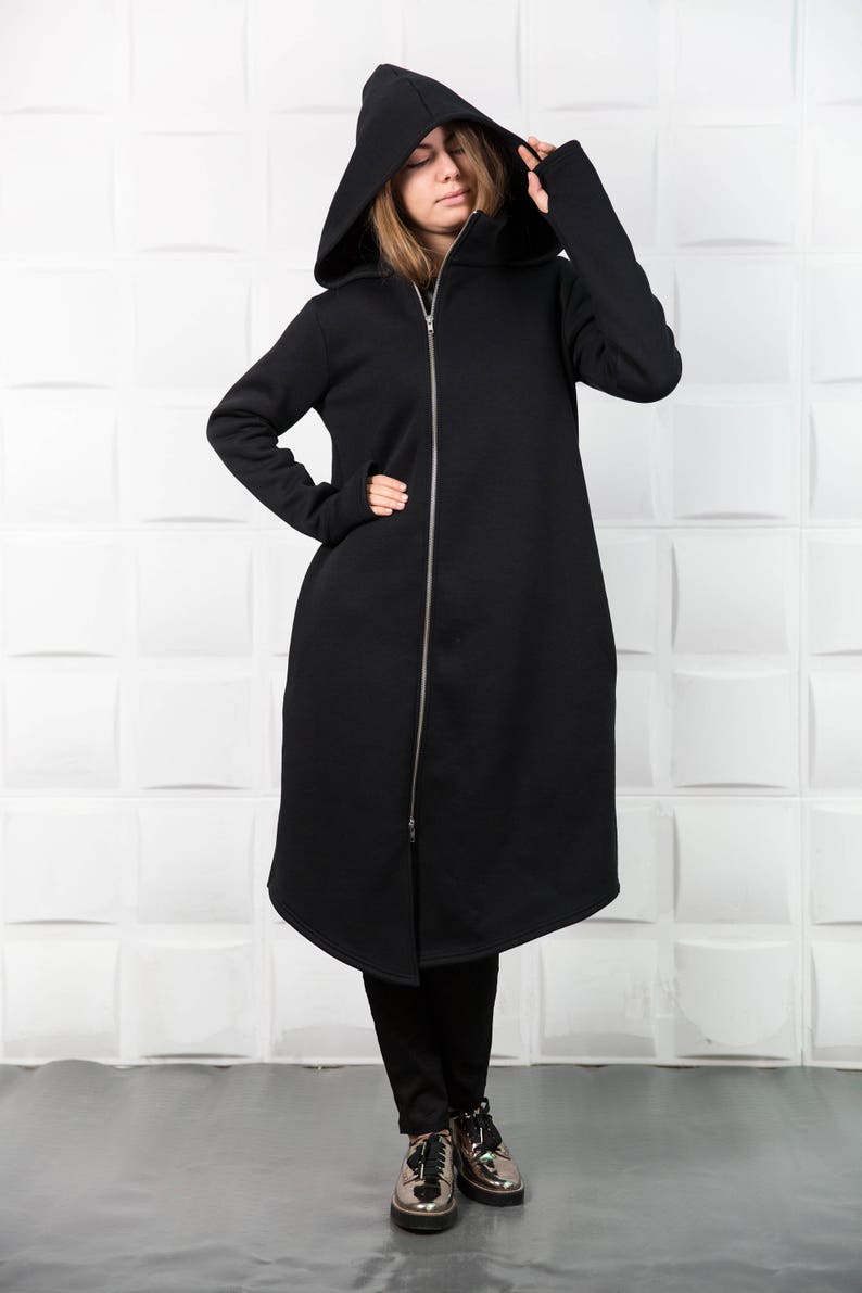 May include: A long black hooded sweatshirt with a zipper down the front. The sweatshirt has a long, flowing design and is made of a soft, comfortable fabric.