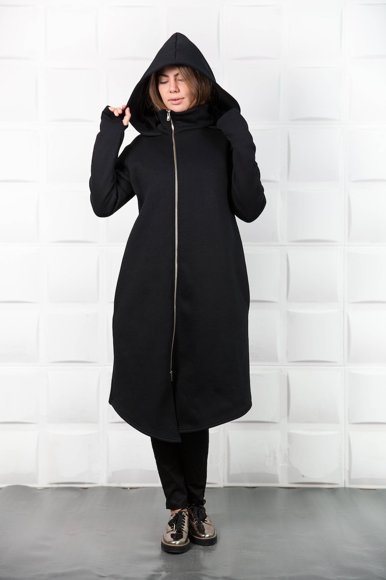 May include: A long black hooded sweatshirt with a zipper closure. The sweatshirt has a high neck and a relaxed fit.