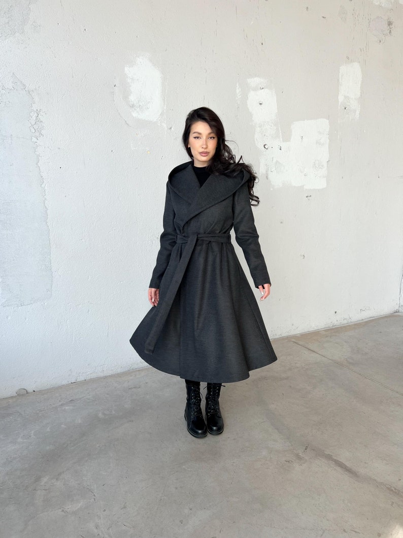 Long hooded coat with a princess-inspired design in warm, heavy wool with soft viscose lining, perfect for winter. Features side pockets and a long belt at the waist for a flattering fit.