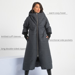 May include: A long, dark grey puffer coat with a warm cosy hood, knitted cuff sleeves, and a long double-sided zipper. The coat has functional side pockets.