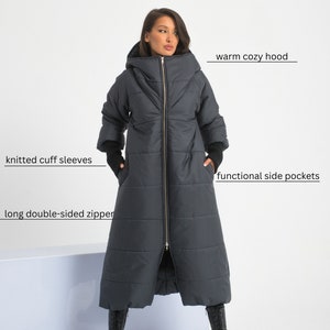 May include: A long, dark gray puffer coat with a warm cozy hood, knitted cuff sleeves, and a long double-sided zipper. The coat has functional side pockets.