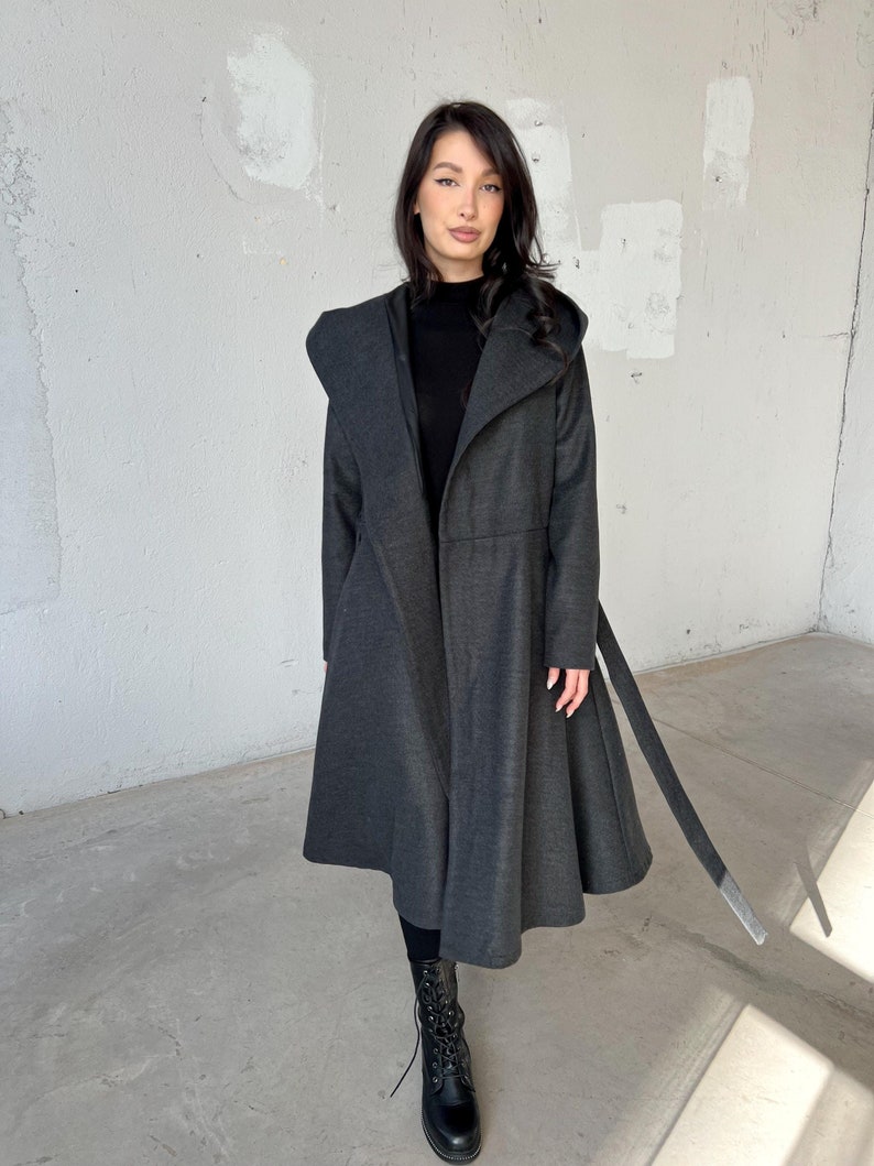 Long hooded coat with a princess-inspired design in warm, heavy wool with soft viscose lining, perfect for winter. Features side pockets and a long belt at the waist for a flattering fit.