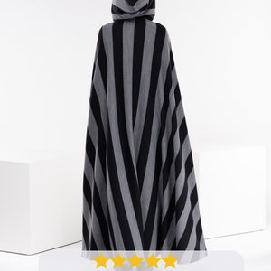 May include: A black and gray striped hooded cape. The caption reads: "The quality of the item is amazing! It is definitely worth the prize, it's gorgeously long, and the hood stays on your head perfectly, no falling down! And the wool is amazing quality (i already said that didn't i)?! The delivery was also super fast // well guessed."