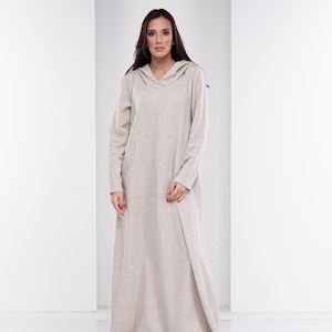 May include: A long, beige linen dress with a hood and a V-neck. The dress has a relaxed fit and a flowing silhouette.