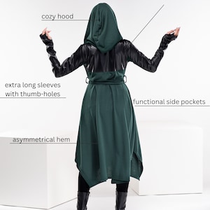 May include: A dark green hooded jacket with long sleeves, faux leather accents on the back and sleeves, functional side pockets, and an asymmetrical hem.