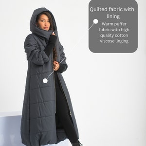 May include: A long, dark blue quilted coat with a high collar and a zip closure. The coat has a warm puffer fabric with high quality cotton viscose lining.  "Quilted fabric with lining" and "Warm puffer fabric with high quality cotton viscose lining" are written in white text on a grey background.