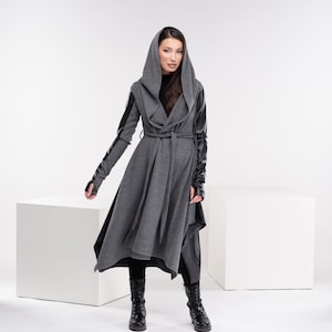 May include: A gray hooded wrap coat with black leather sleeves and a black belt. The coat has a long, flowing silhouette and a relaxed fit.