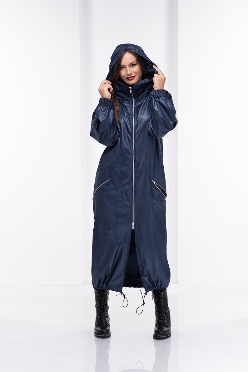 May include: A long navy blue raincoat with a hood, zipper closure, and two pockets. The raincoat has a drawstring at the bottom.
